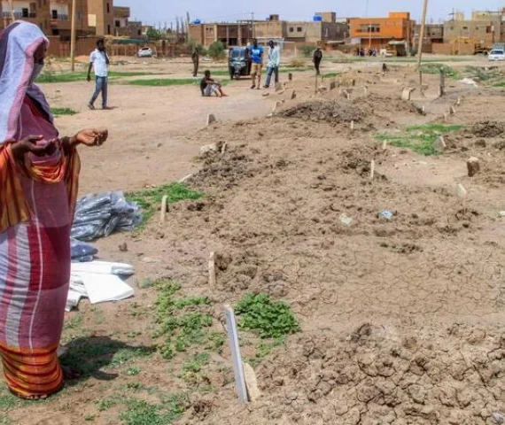 a woman prays by one of the makeshift graves of those buried in khartoum s southern suburb of al azhari on august 2 2025 when the area was under control of the rapid support forces rsf paramilitaries which will be exhumed for reburial in the local cemetery photo afp