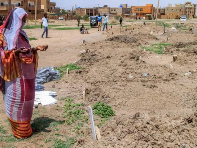 a woman prays by one of the makeshift graves of those buried in khartoum s southern suburb of al azhari on august 2 2025 when the area was under control of the rapid support forces rsf paramilitaries which will be exhumed for reburial in the local cemetery photo afp
